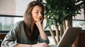 Junge Frau sitzt vor Laptop