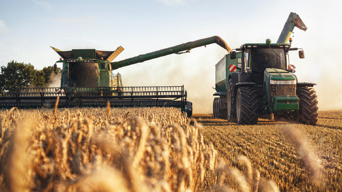 Mähdrescher und Traktor bei der Ernte auf einem Weizenfeld