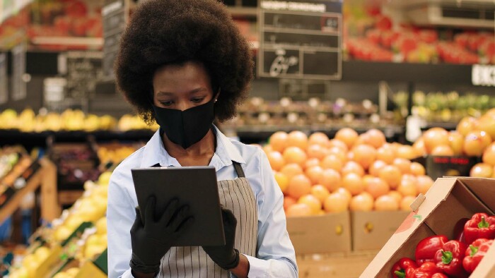 © VAKSMANV, stock.adobe.com Arbeiterin im Supermarkt mit Maske und Handschuhen