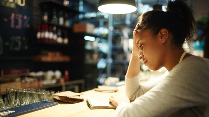 © pressmaster, stock.adobe.com Müde Kellnerin, die am Ende des Arbeitstages Notizen zu Bestellungen und Trinkgeldern liest