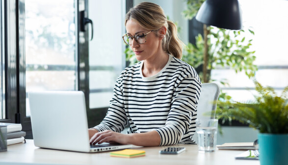 Frau arbeitet in Büro an Laptop