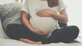 Schwangere Frau fasst sich an den Bauch
