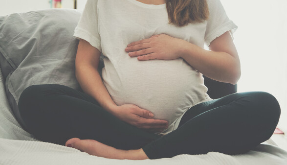 Schwangere Frau fasst sich an den Bauch