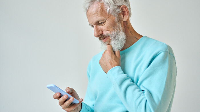 Älterer Herr mit Bart schaut auf sein Handy © insta_photos, stock.adobe.com