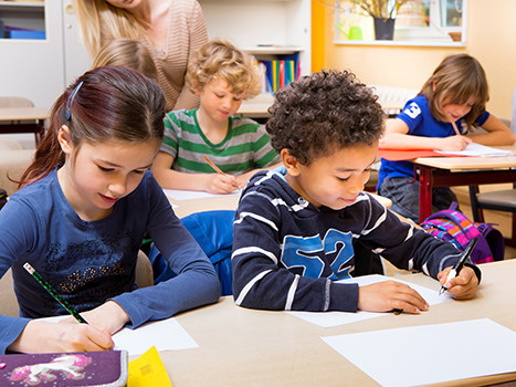 Schüler/-innen sitzen in der Schulklasse und schreiben