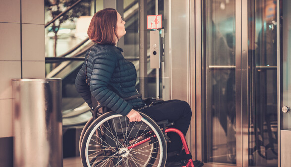 Rollstuhlfahrerin vor Lifttür