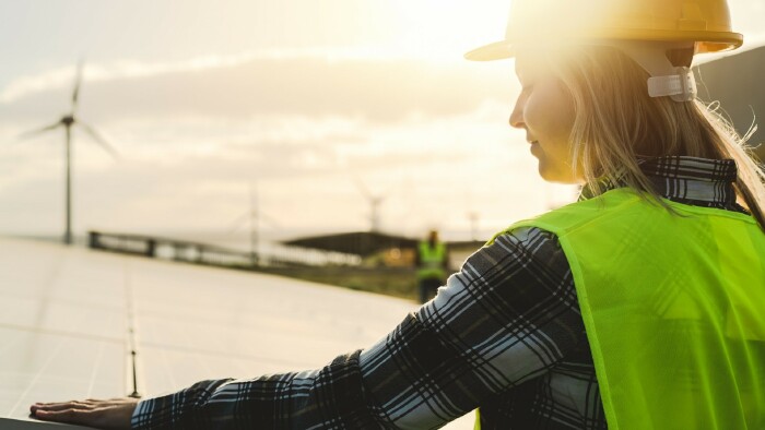 © Alessandro Biascioli, stock.adobe.com Junge Ingenieurin im Einsatz für alternative Energien mit Windrad und Solarpanel