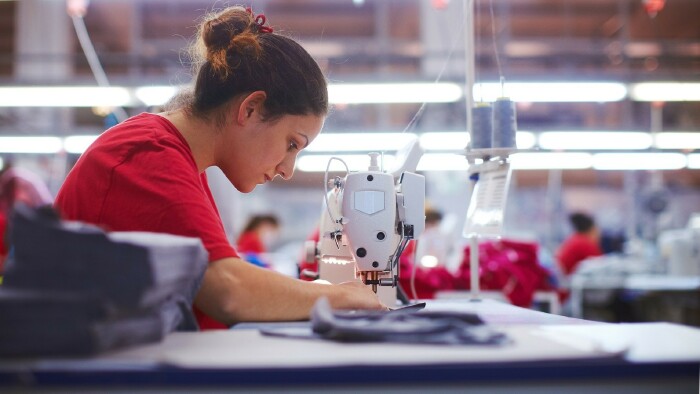 Junge Schneiderin arbeitet an einer Nähmaschine in einer Textilfabrik