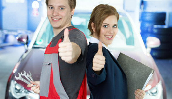 Mann in Arbeitshose und Frau im Anzug stehen vor einem Fahrzeug in einer Werkstatt und geben beide einen Daumen nach oben. © Karin & Uwe Annas, stock.adobe.com