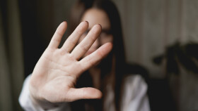Unscharf abgebildete Frau h&auml;lt ihre Hand als Stoppsignal in die Kamera