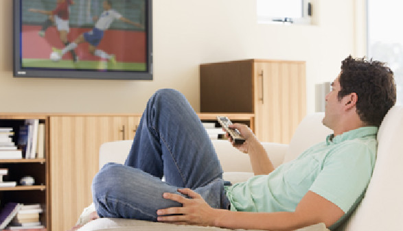 Junger Mann liegt auf der Couch und schaut Fernsehen. © Monkey Business, Fotolia