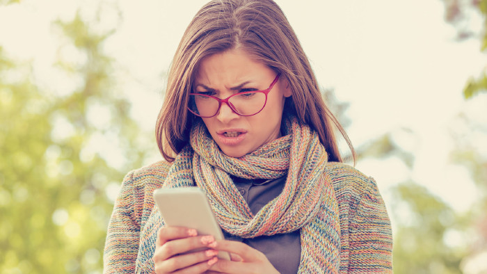 Frau blickt verwundert auf ihr Handy