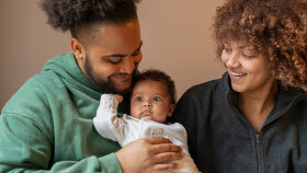 Eltern schauen ihr kleines Baby liebevoll lächelnd an