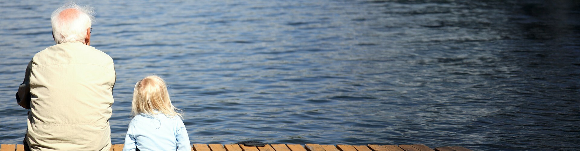 Opa und Enkerl blicken vom Steg aus auf einen See