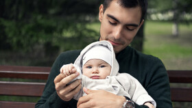 Vater sitzt mir Baby auf einer Parkbank