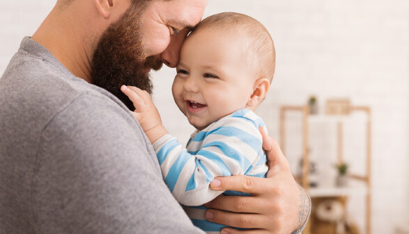 Vater legt den Kopf an die Stirn seines lachenden Babys
