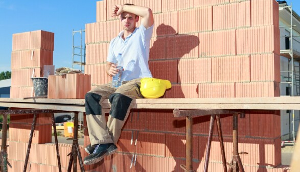 Bauarbeiter arbeitet in der prallen Sonne.