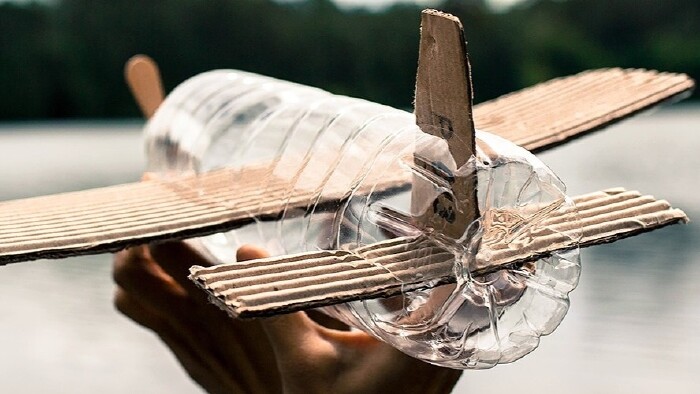 Kinderflugzeug aus einer PVC Flasche und Kartonflügeln gebastelt segelt über einen See
