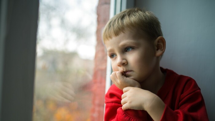 Kleiner Bub sitzt nachdenklich am Fenster