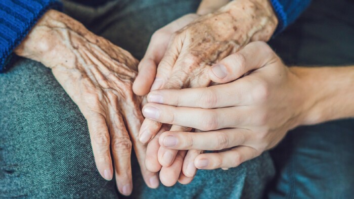Hände einer jungen Frau greifen nach den Händen einer alten Frau