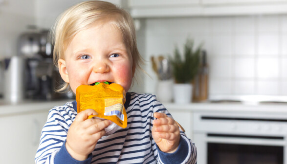 Kind isst Obstbrei aus der T&uuml;te