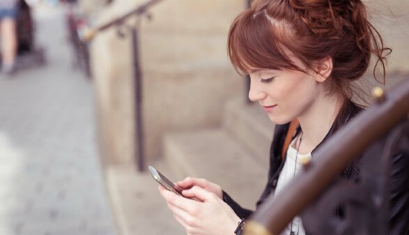 Junge Frau sitzt draußen auf einer Treppe und schaut auf ihr Handy © Gegensatz dazuwerkstatt, stock.adobe.com