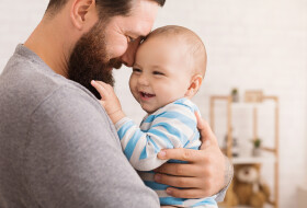 Vater legt den Kopf an die Stirn seines lachenden Babys