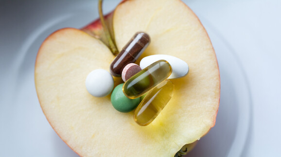 Nahrungserg&auml;nzung - Pillen,Tabletten und Kapseln auf einem Apfel