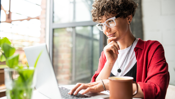 Beschäftigte junge elegante Frau mit Brille, die auf Laptop-Display schaut