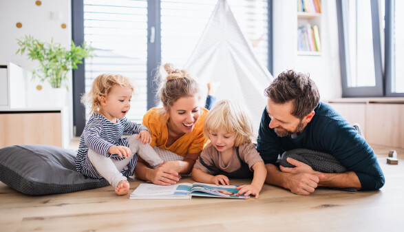 Familie liest am Boden ein Buch