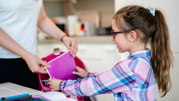 Mutter hilft Tochter beim Packen der Schultasche