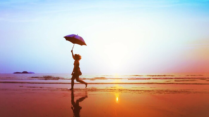 Silhouette eines glücklichen Mädchens mit Sonnenschirmsprung am Strand 