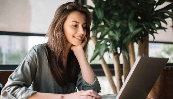 Junge Frau sitzt vor Laptop