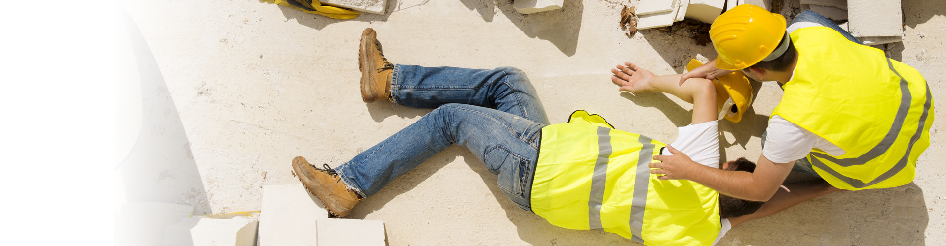 Ein Arbeiter auf der Baustelle beugt sich über einen zweiten Arbeiter, der am Boden liegt © Halfpoint, stock.adobe.com
