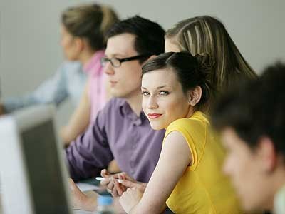 Schülerin sitzt mit MitschülerInnen in einer Reihe vor Computern und schaut direkt in die Kamera © auremar, Fotolia.com TeilnehmerInnen im Kurs © auremar, Fotolia.com