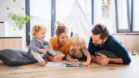 Familie liest am Boden ein Buch