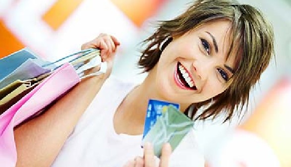 Lächelnde Frau hält mehrere Einkaufstaschen in der einen, zwei Kreditkarten in der anderen Hand. © Yuri Arcurs, Fotolia.com
