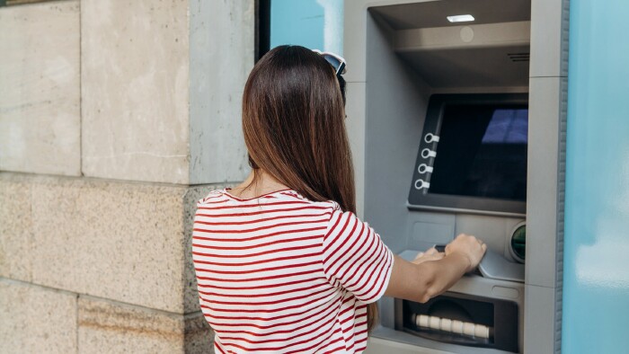 Junge Frau hebt beim Bankomaten Geld ab.