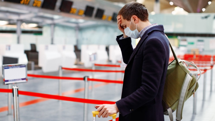 Mann steht mit Koffer am Flughafen beim CheckIn