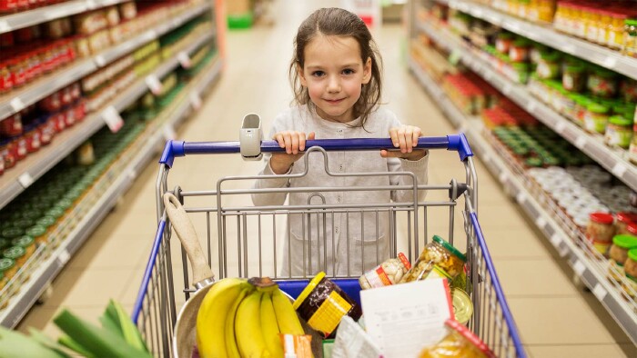 Mädchen mit Essen im Einkaufswagen im Supermarkt