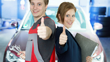 Mann in Arbeitshose und Frau im Anzug stehen vor einem Fahrzeug in einer Werkstatt und geben beide einen Daumen nach oben. © Karin & Uwe Annas, stock.adobe.com
